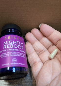 A bottle of pills and a hand holding 1 pill